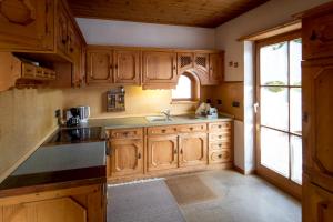 eine Küche mit Holzschränken, einem Waschbecken und einem Fenster in der Unterkunft Haus Sonnseitn Murau für 6 bis 8 Personen in Sankt Egidi