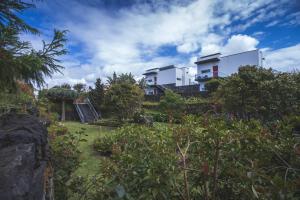 uma casa no topo de uma colina com um jardim em Quinta De Santana em Rabo de Peixe