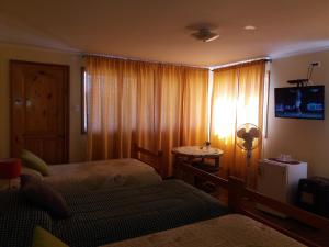 a bedroom with two beds and a window with a television at Alojamiento Valle Verde in Isla de Maipo