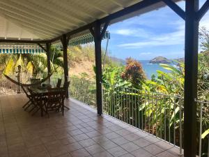 porche con mesa, sillas y vistas al océano en Villa Figues et Mangos, en Terre-de-Haut