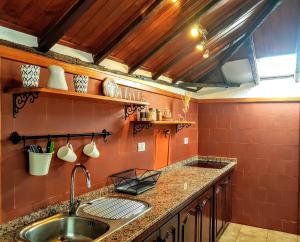 een keuken met een wastafel en een rode muur bij Casa Rural LAS TIAS II in Tijarafe