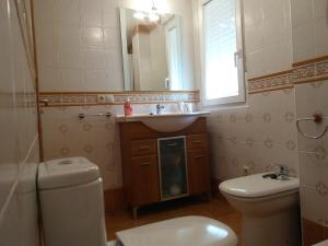 a bathroom with a sink and a toilet and a mirror at CASA CHALET ATALAYA a pie de playa en Laxe in Laxe +30 photos