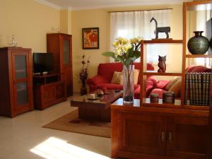 a living room with a red couch and a vase with flowers at CHALET ATALAYA a pie de playa en Laxe in Laxe