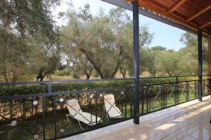 two chairs on a balcony with trees in the background at VILLA ERMIONI in Melíkia