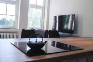 a living room with a table and a tv at Alte Schule Gästehaus - The principal's rooms Appartment in Bitburg