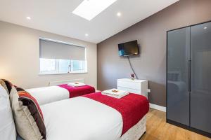 2 letti in una camera da letto con TV e finestra di South Woodford 2 Bed En-Suite House a Londra