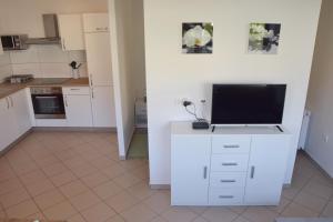una cocina con armarios blancos y TV en una encimera en COMFY and BRIGHT Apartment, en Kranj