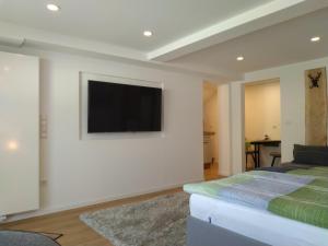 1 dormitorio con TV de pantalla plana en una pared blanca en Kleines Moselchalet en Cochem