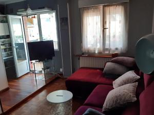 a living room with a red couch and a tv at Ático con terraza céntrico Oviedo in Oviedo