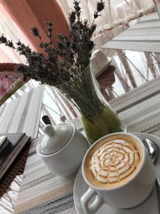 a cup of coffee on a table with a vase of flowers at Отель Буржуа in Zhytomyr