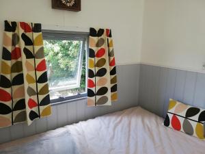 a bedroom with curtains and a bed with a window at The Hut at Downlands in Warminster