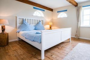 a bedroom with a white bed and two windows at Der historische Silberhof von 1856 in Pellworm