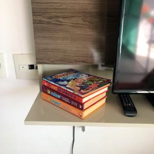 ein Stapel Bücher, die auf einem Schreibtisch neben einem Computer liegen in der Unterkunft Localização PRIVILEGIADA Beach Class Iracema in Fortaleza