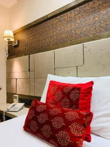 uma cama com uma almofada vermelha numa cama branca em THE SINGH EMPIRE, New Delhi em Nova Deli
