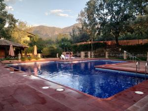a swimming pool in a backyard with mountains in the background at Aldea Vetonia Resort Familiar- PISCINAS-4 Zonas infantiles y deportivas 4 ACTIVIDADES AL DIA HASTA EL 8 DE SEPTIEMBRE CON MONITORES "SE ACEPTAN MASCOTAS DESDE EL 28 DE AGOSTO" in Hervás
