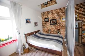 a bedroom with a bed and a brick wall at Apartament Gra - Gothic House in Toruń