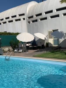 a swimming pool with two umbrellas and a building at Villa Tranquilla in Riposto
