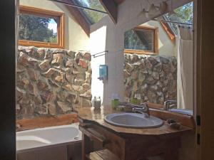 a bathroom with a sink and a stone wall at Complejo Duendes del Maiten in San Carlos de Bariloche