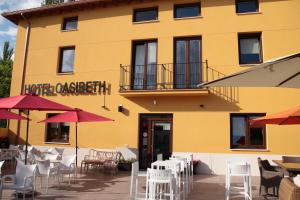 a yellow building with tables and chairs and umbrellas at Hotel Rural Oasibeth in Frómista