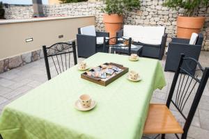 a green table with a tray of cups and saucers on it at FILANNA HOME RELAX in San Vito lo Capo