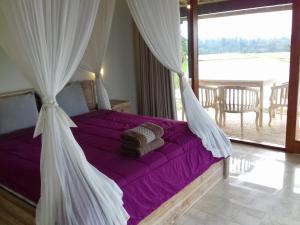 a bedroom with a bed with purple sheets and a window at KUBU D'UME HOMESTAY in Jatiluwih