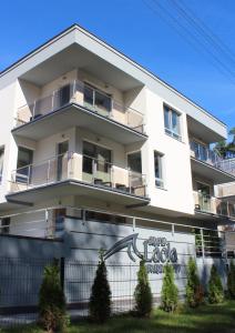 een wit gebouw met een hek ervoor bij Apartament Mariva B03 z ogródkiem - Pobierowo - blisko morza - przy kompleksie Grand Laola SPA in Pobierowo