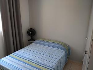 ein kleines Schlafzimmer mit einem Bett und einem Ventilator in der Unterkunft Residencial in Belo Horizonte