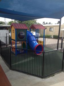 a playground with a blue slide in a fence at Blackwater Hotel Motel in Blackwater