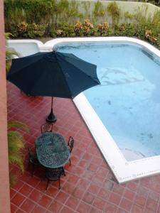 an umbrella and a chair next to a swimming pool at Balcon Gueela in Santa Cruz Huatulco