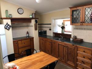 cocina con armarios de madera y mesa de madera en Greenock's Old Telegraph Station, en Greenock