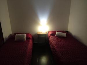 2 camas en una habitación con una luz en la pared en Depto 4 en San Clemente del Tuyú