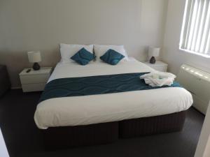 a bedroom with a large bed with blue pillows at Sussex Shores in Sussex Inlet