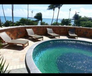 a swimming pool with chaises and chairs and the ocean at Apto Beira Mar 2102 in Fortaleza