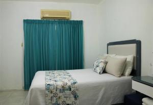 1 dormitorio con 1 cama con cortina verde en HOTEL VILLAS DEL MAR, en Pedernales