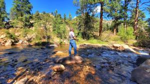 a man is standing on rocks in a river at The Inn on Fall River & Fall River Cabins in Estes Park