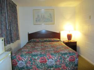 a bedroom with a bed with a floral bedspread and a lamp at Relax Inn - Cottage Grove in Cottage Grove