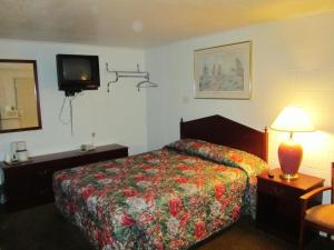 コテージ・グローブにあるRelax Inn - Cottage Groveのベッド1台、壁掛けテレビが備わるホテルルームです。