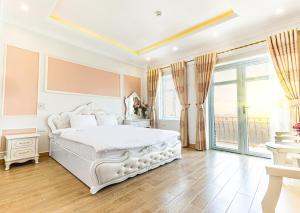 a white bedroom with a bed and a large window at An loc hotel in Diện Biên Phủ