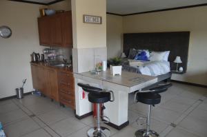 a kitchen with a bed and a kitchen island with bar stools at Oppidam Self Catering Accommodation in Clanwilliam