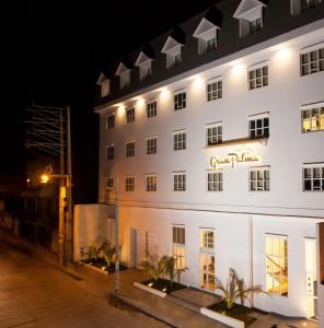 un bâtiment blanc avec un panneau sur lui la nuit dans l'établissement Hotel Gran Palma Huancayo, à Huancayo