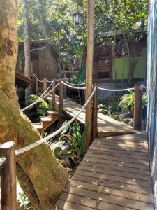 a wooden walkway in a garden with a fence at Pousada Piratas do Embaú in Guarda do Embaú