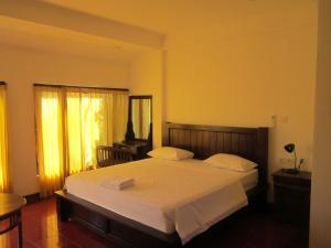 1 dormitorio con 1 cama grande con sábanas blancas en Tutick House en Ubud