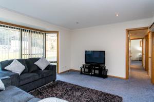 a living room with a couch and a flat screen tv at Acton Park Holiday Units in Acton Park