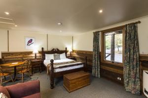 um quarto com uma cama, uma mesa e uma janela em Cradle forest inn em Moina