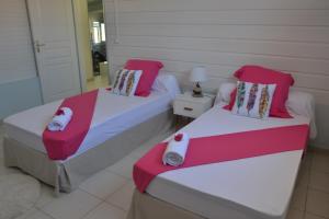 two beds with red and white sheets in a room at Villa BONHEUR & Co _ Spa in Rivière-Salée