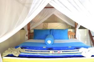 a bed in a tent with blue pillows at Rumah Wayans Lipah in Amed