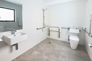 a bathroom with a toilet, sink, and bathtub at Alfred Apartments in Newcastle