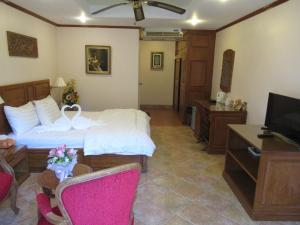 a hotel room with a bed and a television at Villa Oranje Pattaya in Pattaya