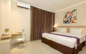 a hotel room with a large bed and a desk at Laxston Hotel in Yogyakarta