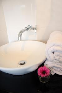 a bathroom sink with towels and a pink flower in a bowl at V Hotel Kuala Lumpur in Kuala Lumpur